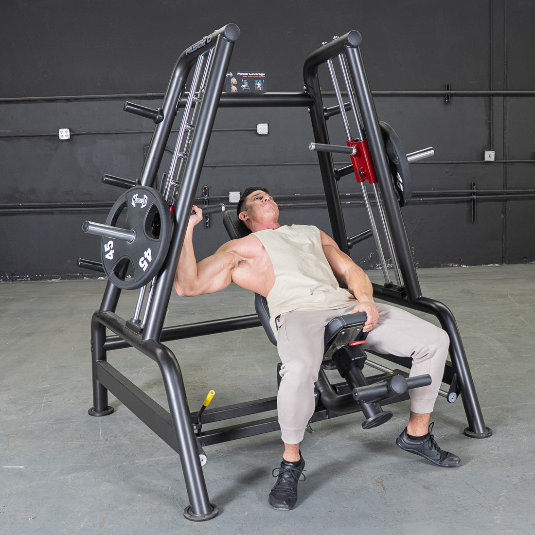 Man using a black leverage bench press machine with 45lb plates in a gym.