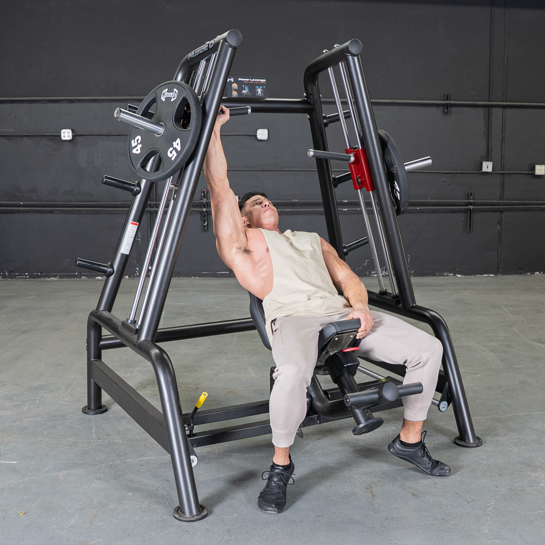 Man using a black leverage bench press machine with a 45lb weight plate.