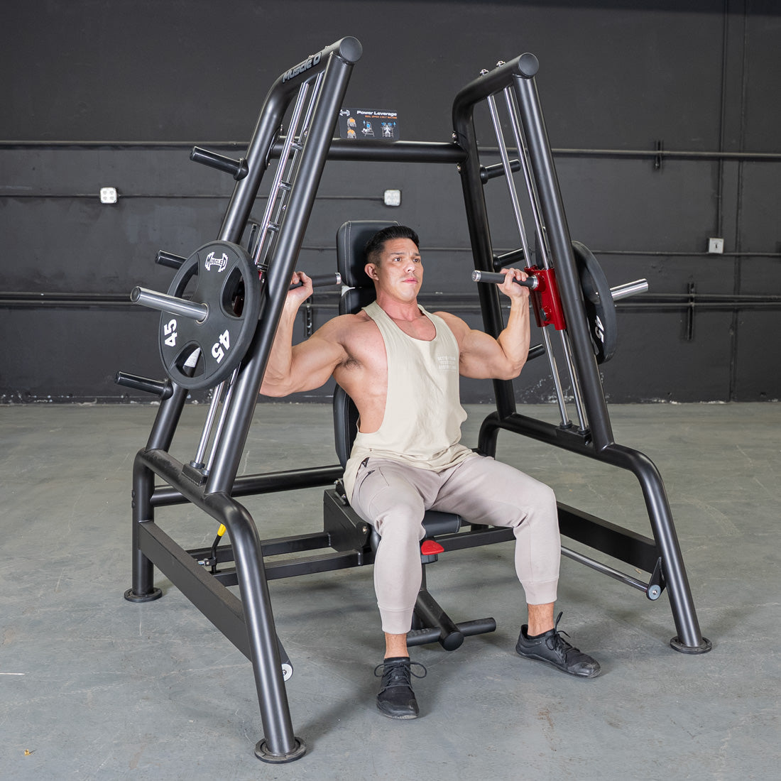 Man using a black Power Leverage V2 Convergent Bench for incline shoulder press, with 45lb plates loaded.