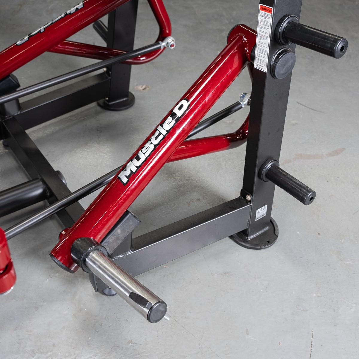 Close-up of a red and black Muscle D Fitness chest fly machine with chrome weight horns and black handles.