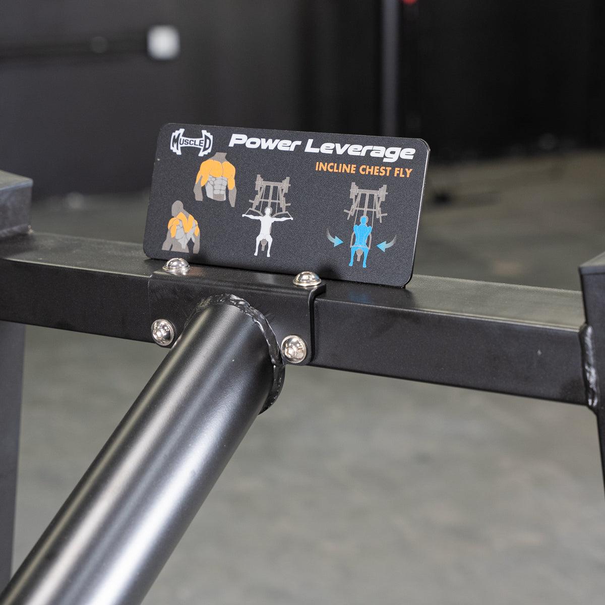Close-up of a black sign on a fitness machine showing "Power Leverage Incline Chest Fly" and exercise diagrams.