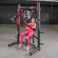 Thumbnail for Woman in pink leopard print workout gear seated on a black and red decline chest press machine.