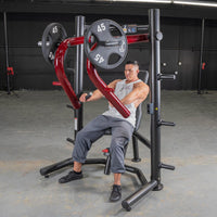 Thumbnail for Man using a red and black decline chest press machine with 45lb weight plates in a gym.