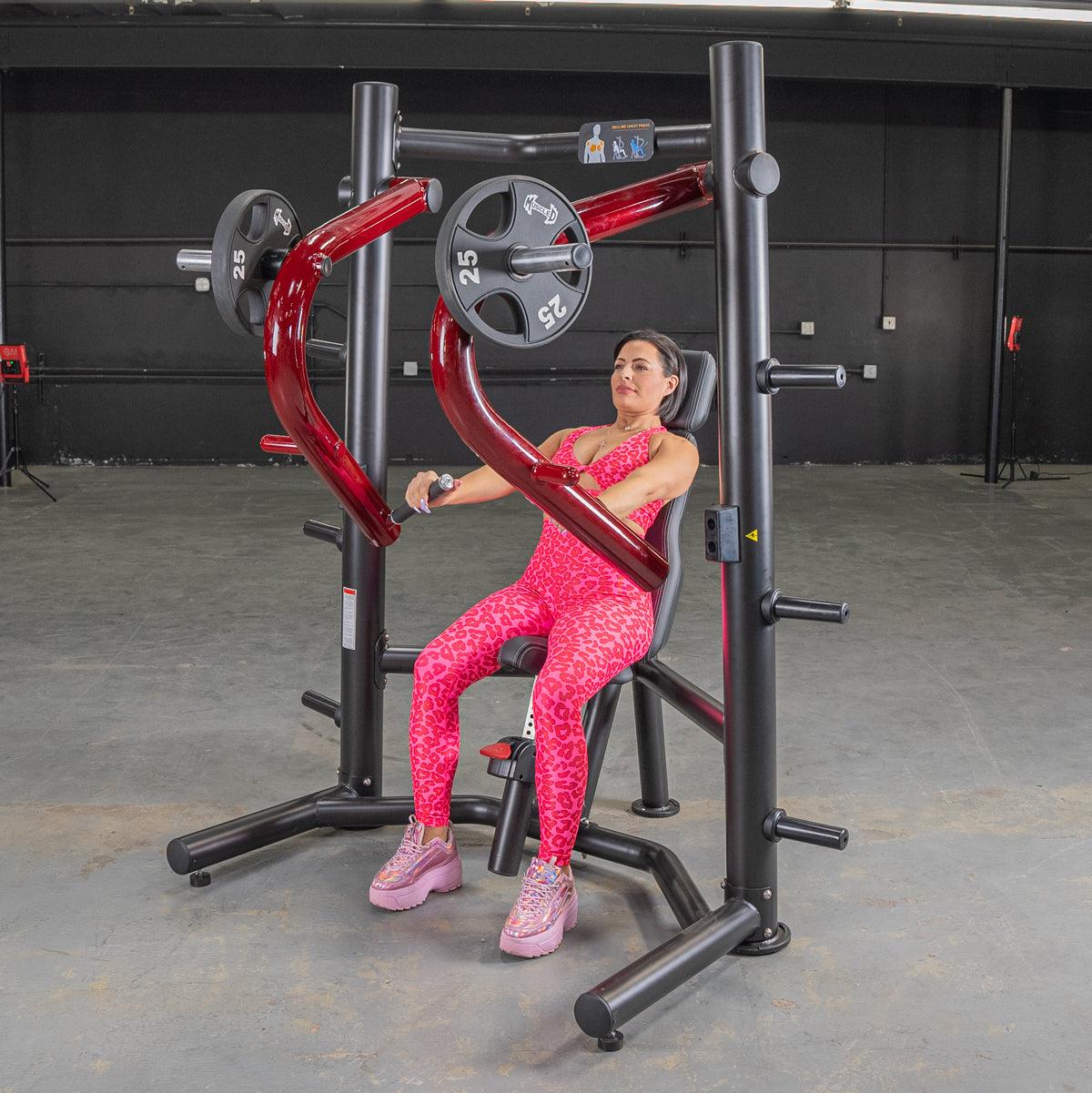 Woman in pink leopard print using a black and red decline chest press machine with weight plates.