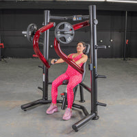 Thumbnail for Woman in pink leopard print using a black and red decline chest press machine with weight plates.