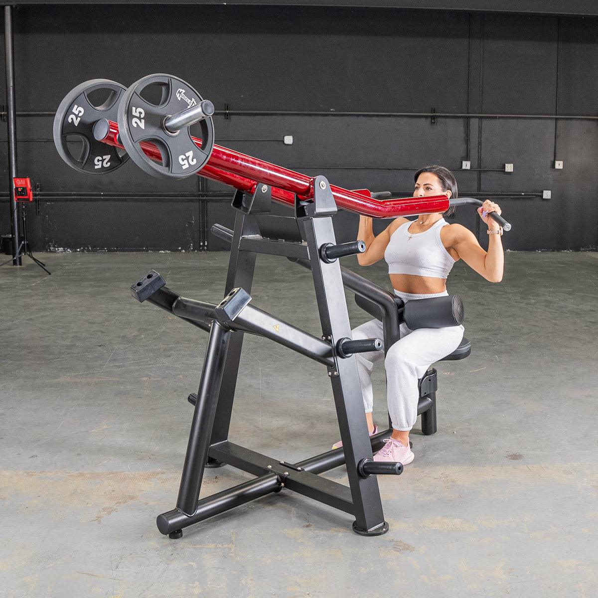 Woman using a red and black iso-lateral lat pull machine with 25lb weight plates in a gym.