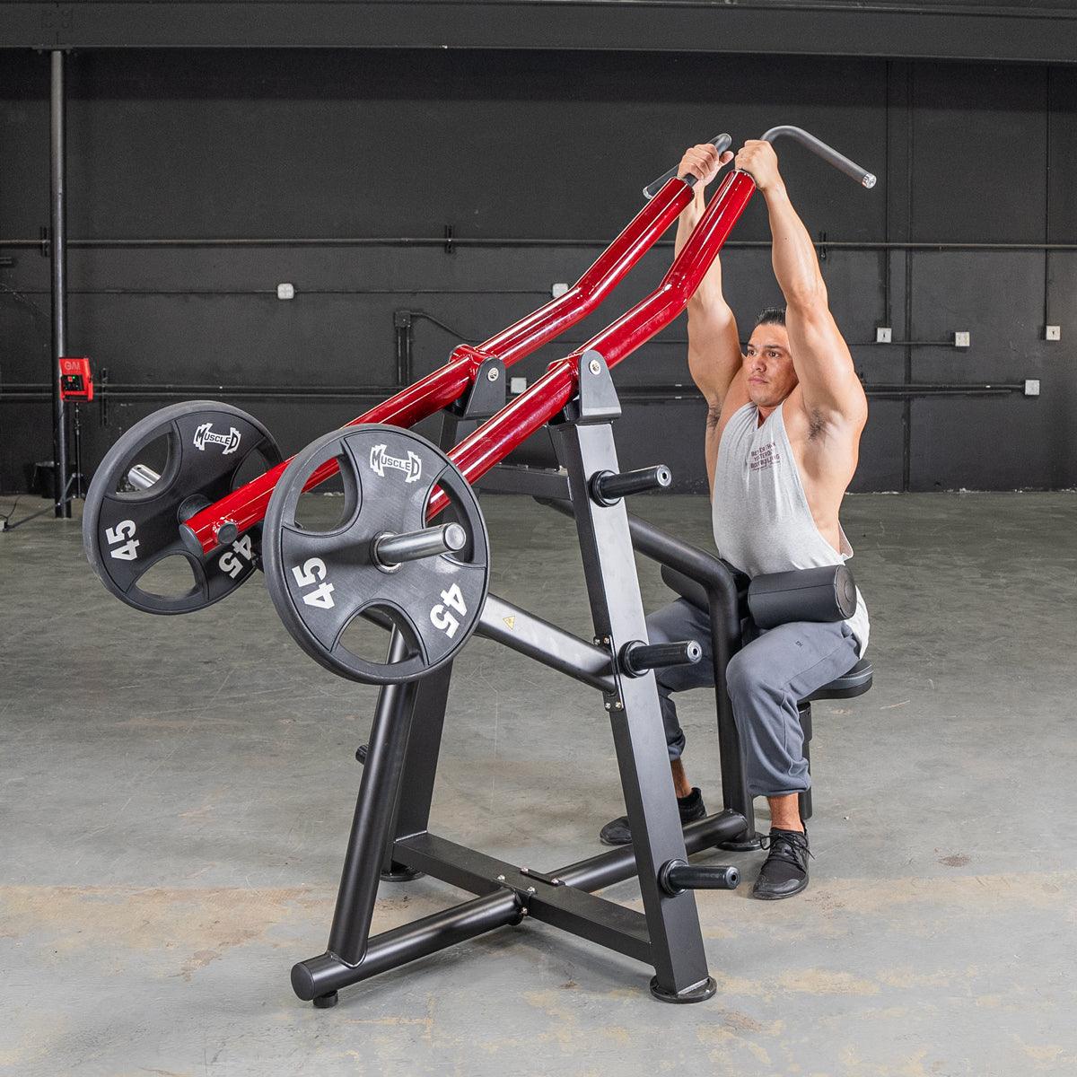 Man using a red and black iso-lateral lat pull machine with weight plates in a gym.
