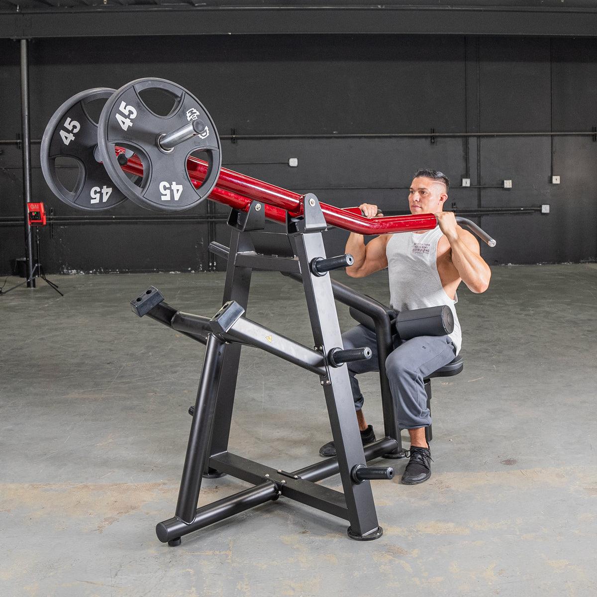 Man using a red and black iso lateral lat pull machine with two 45lb plates in a gym.