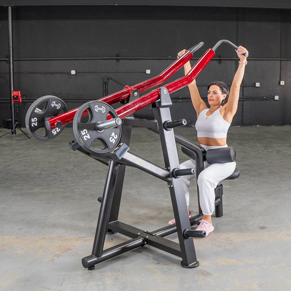 Woman using a red and black lat pull machine with 25lb weights in a gym.