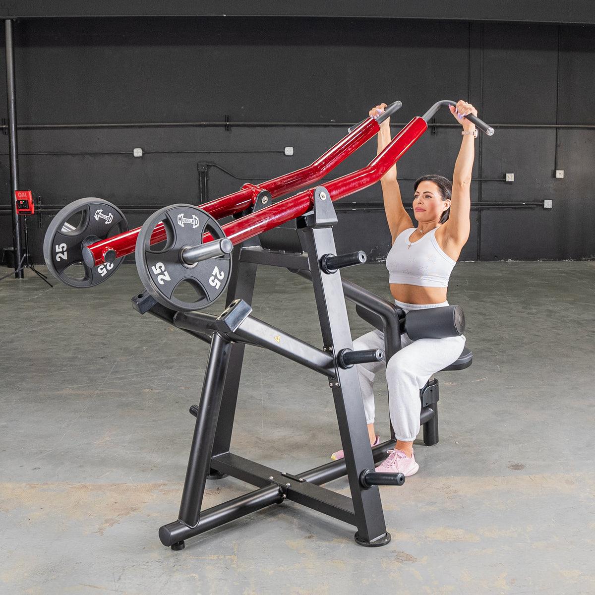 Woman using a red and black iso-lateral lat pull machine with 25lb weights in a gym.