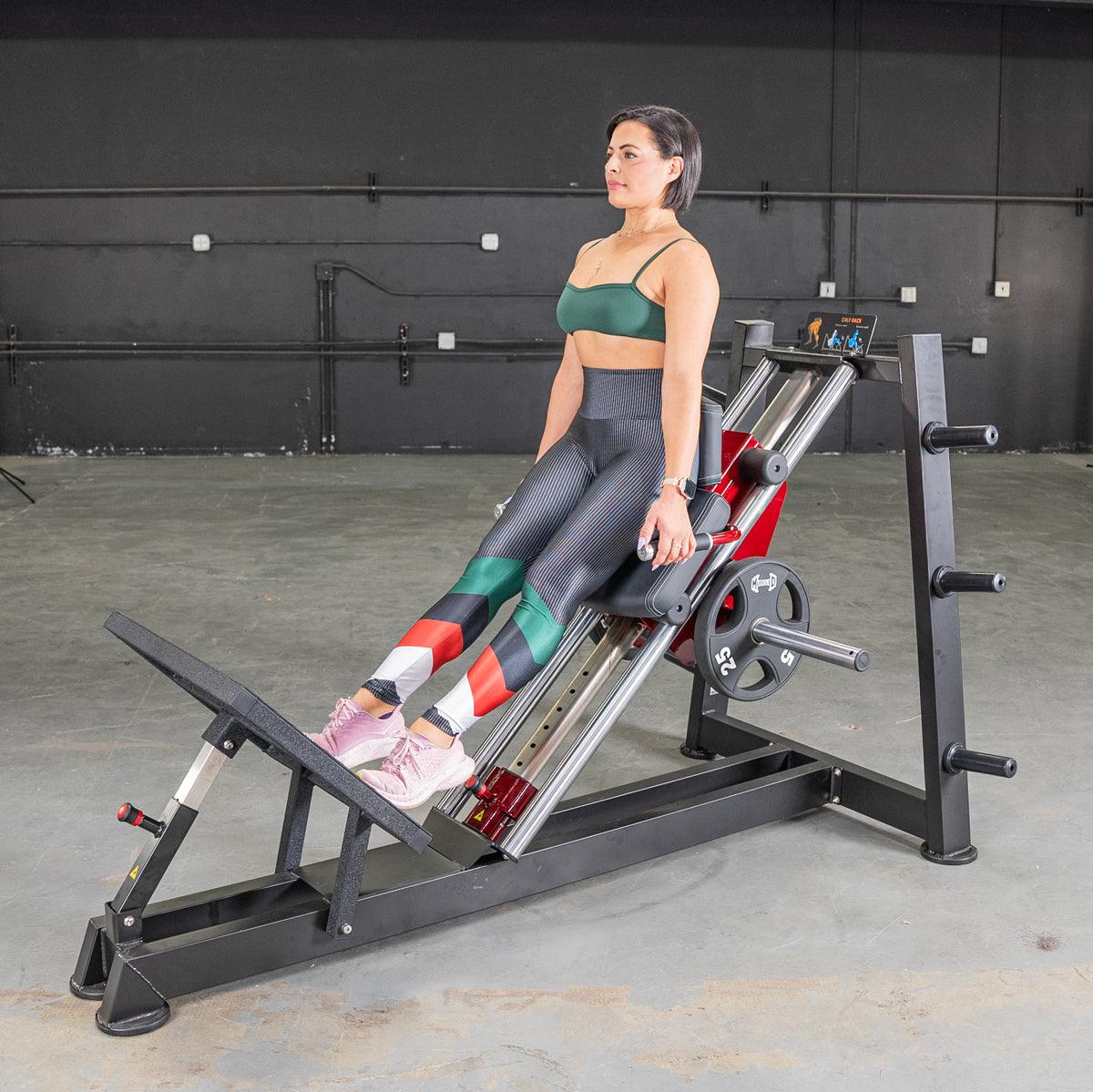 Woman performing a hack squat on a black and red Power Leverage V2 machine with a 25lb weight plate.