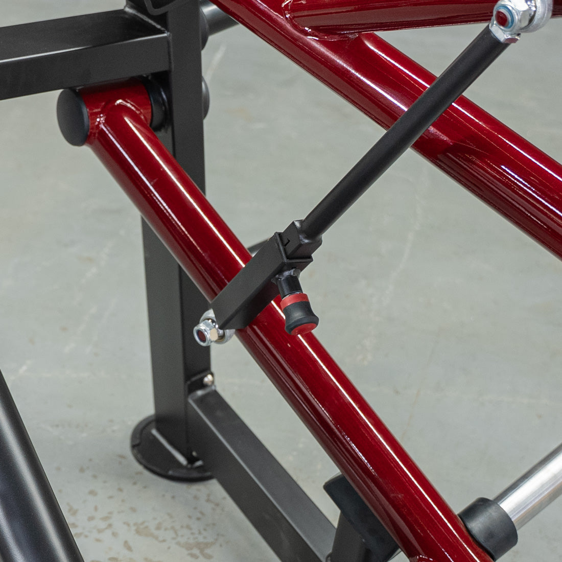 Close-up of a red and black horizontal chest press machine frame with an adjustment knob.