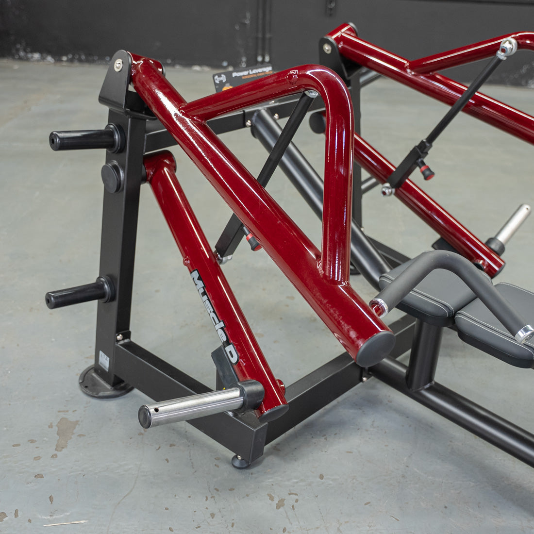 Red and black horizontal chest press machine with a padded seat and handles.