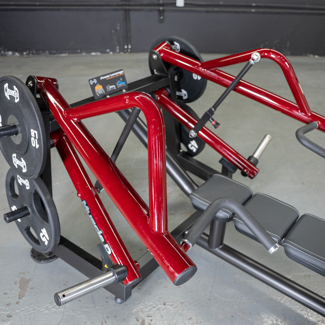Red and black horizontal chest press machine with weight plates in a gym setting.