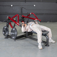 Thumbnail for Person using a red and black horizontal chest press machine with weight plates in a gym.