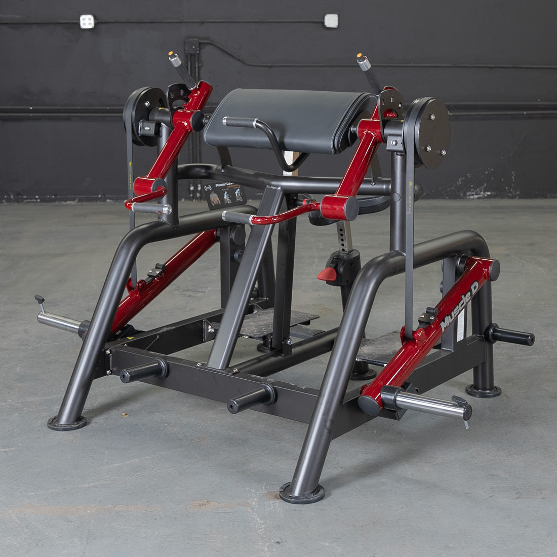 Black and red biceps curl machine with a padded armrest and weight plate holders.