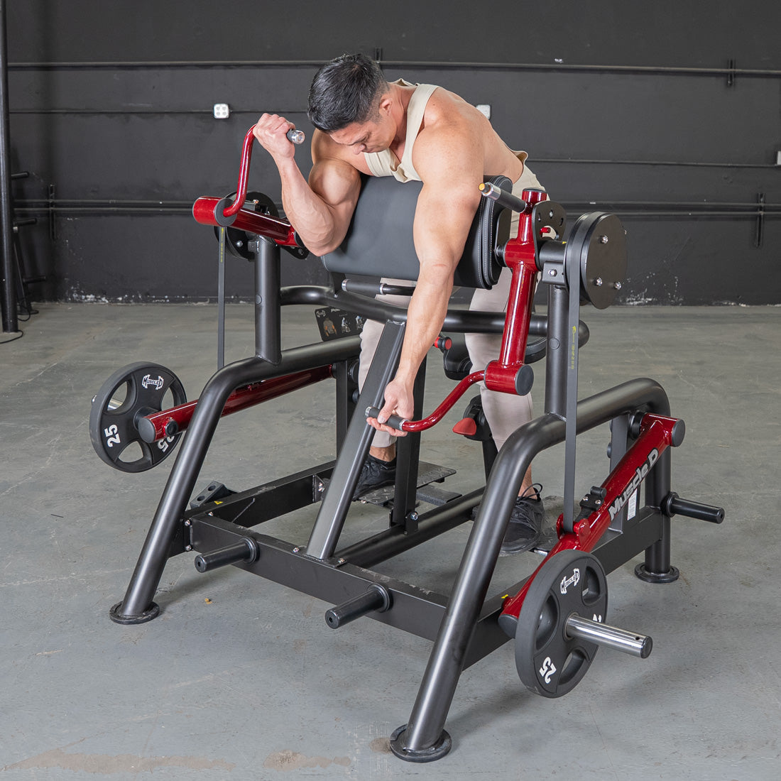 Man using a black and red biceps curl machine with weight plates in a gym.