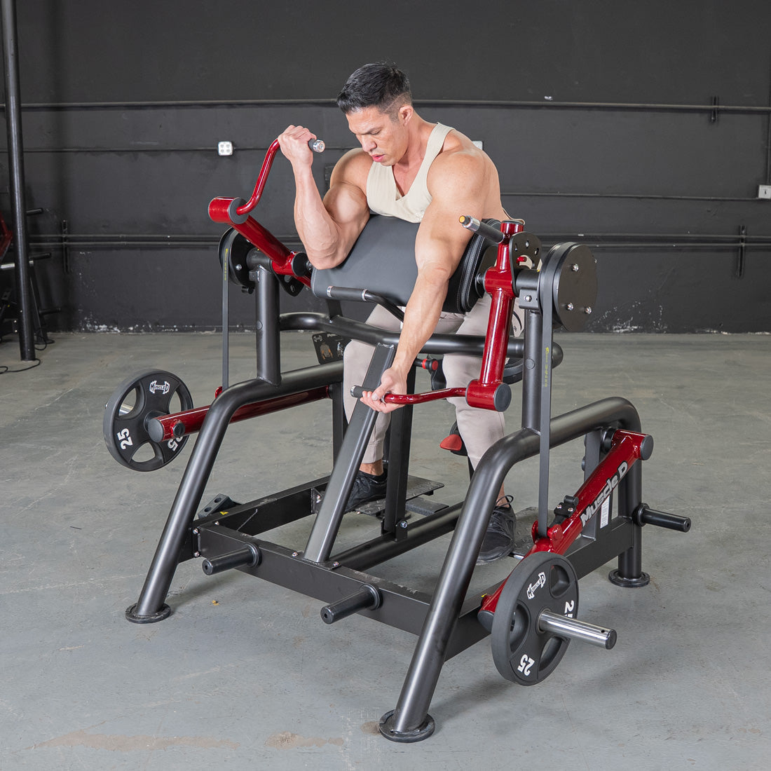 Man using a black and red biceps curl machine with weight plates in a gym.
