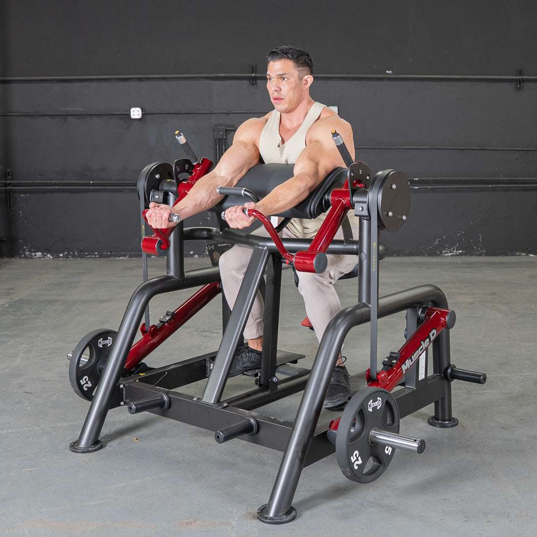 Man using a black and red biceps curl machine with 25lb weights in a gym.