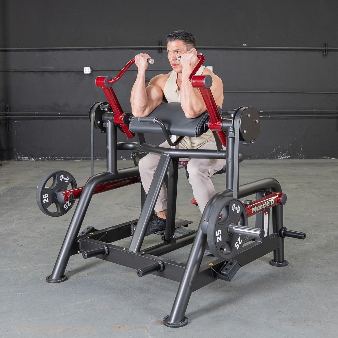 Man using a black and red biceps curl machine with 25lb weight plates.