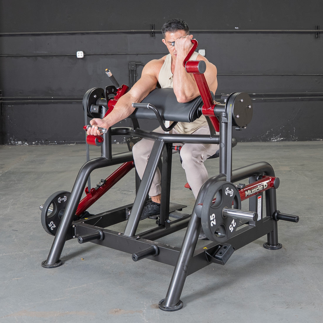 Man using a black and red biceps curl machine with 25lb weights in a gym.