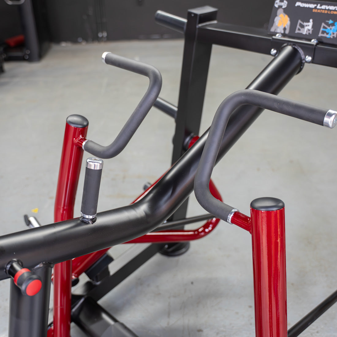 Close-up of the black and red frame of a seated row machine with multiple grip handles.