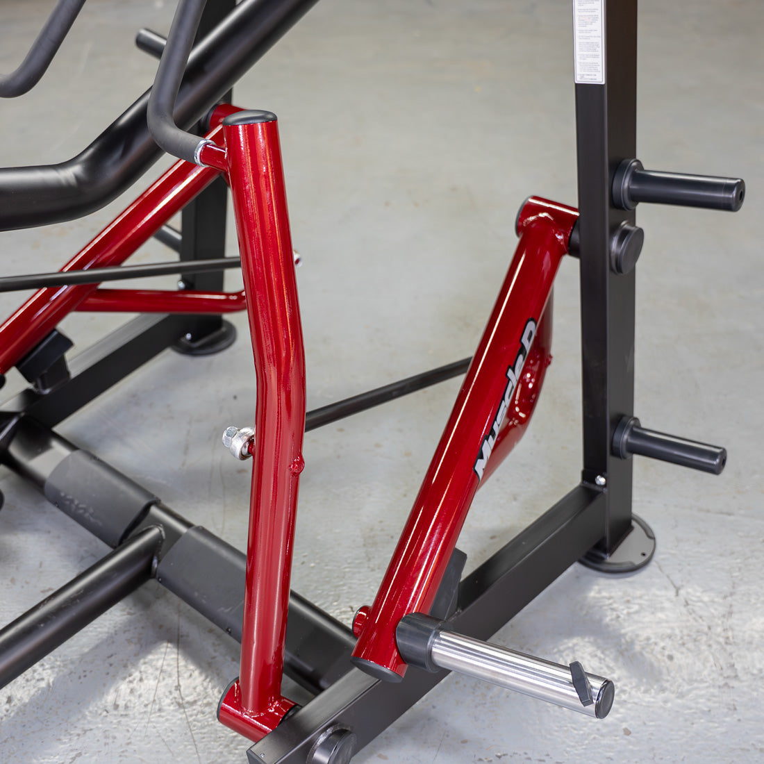 Close-up of the red frame and black weight plate holders of a Muscle D Fitness Iso-Lateral Seated Row machine.