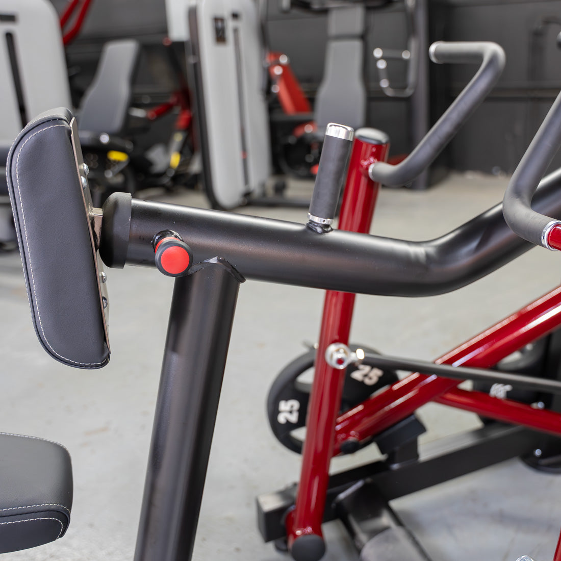 Close-up of a red and black iso-lateral seated row machine with a padded chest rest and handles.
