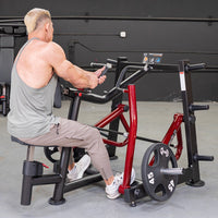 Thumbnail for Man in gray tank top using a red and black seated row machine with 45lb weight plates.