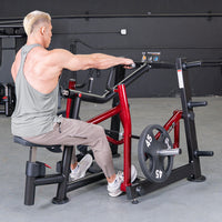 Thumbnail for Man in a grey tank top using a red and black seated row machine with a 45lb weight plate.
