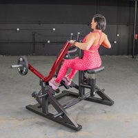 Thumbnail for Woman in pink leopard print using a red and black seated row machine with a 25lb weight plate.
