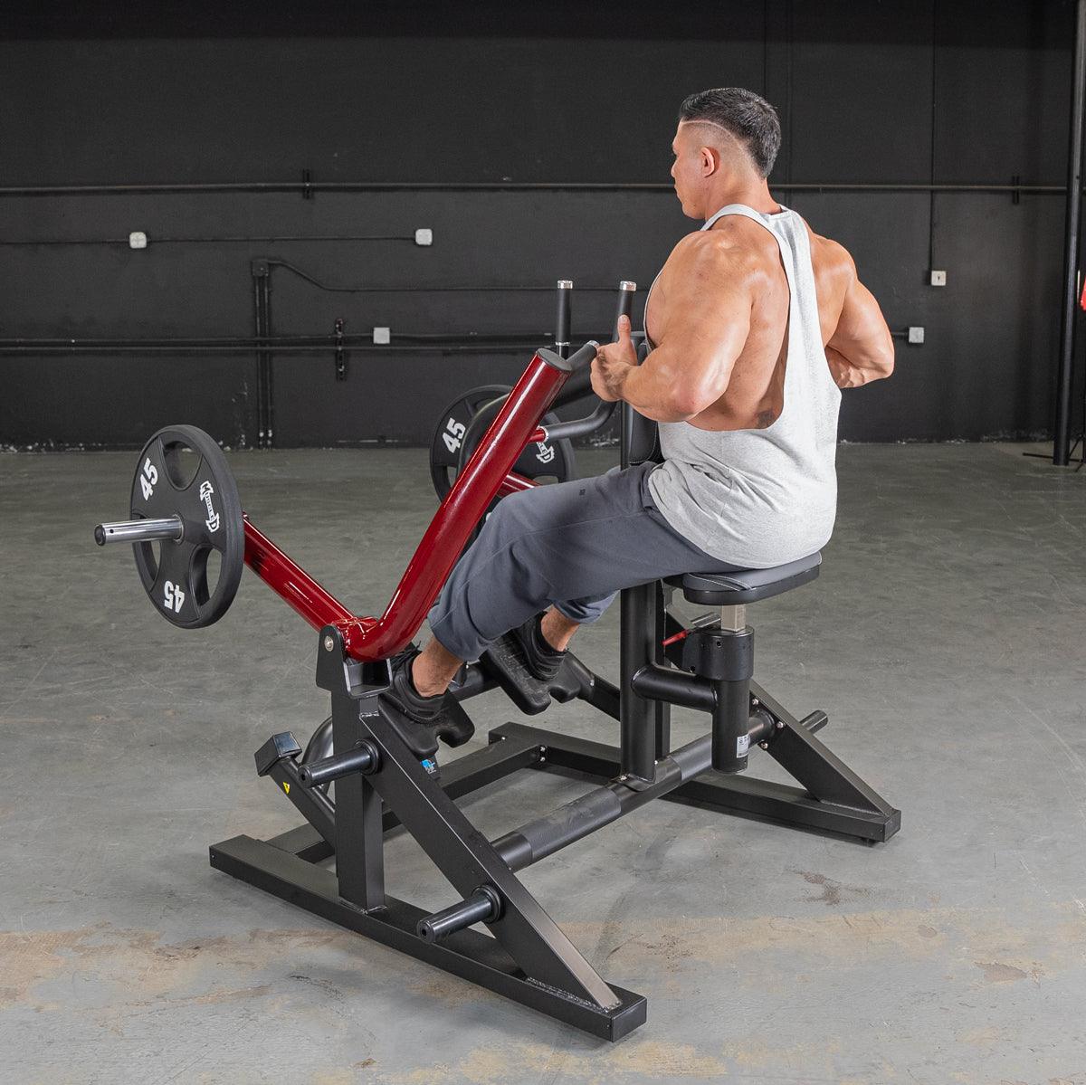 Man using a red and black seated row machine with weight plates in a gym.