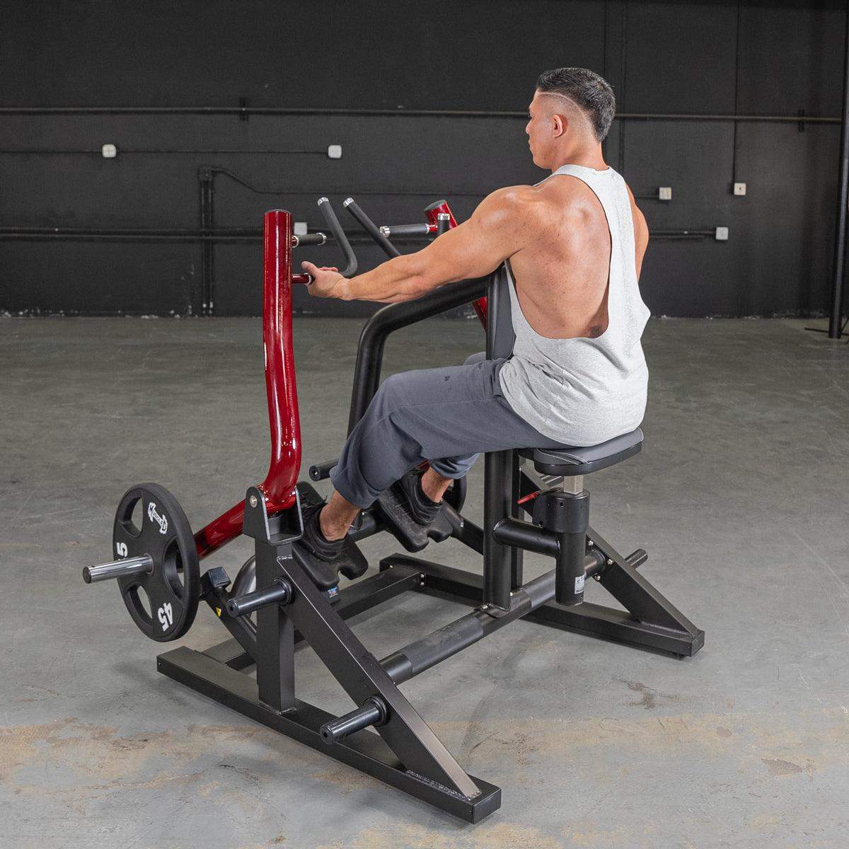 Man using a red and black seated row machine with a 45lb weight plate in a gym.