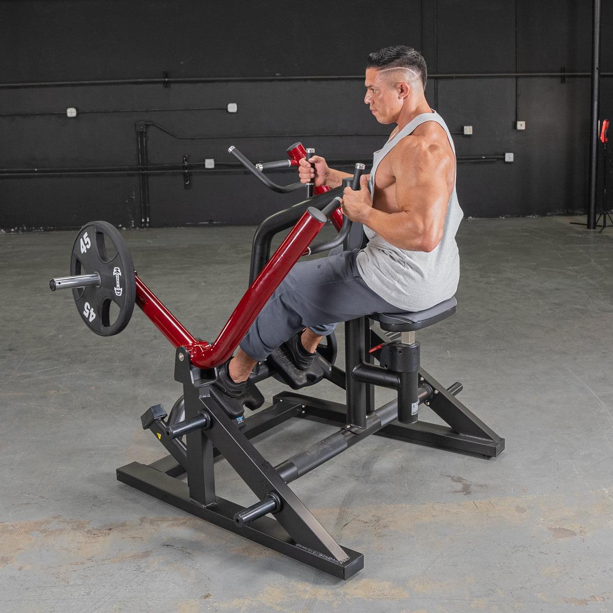 Man in a gray tank top using a red and black seated row machine with a 45lb weight plate.