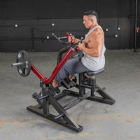 Thumbnail for Man in a gray tank top using a red and black seated row machine with a 45lb weight plate.