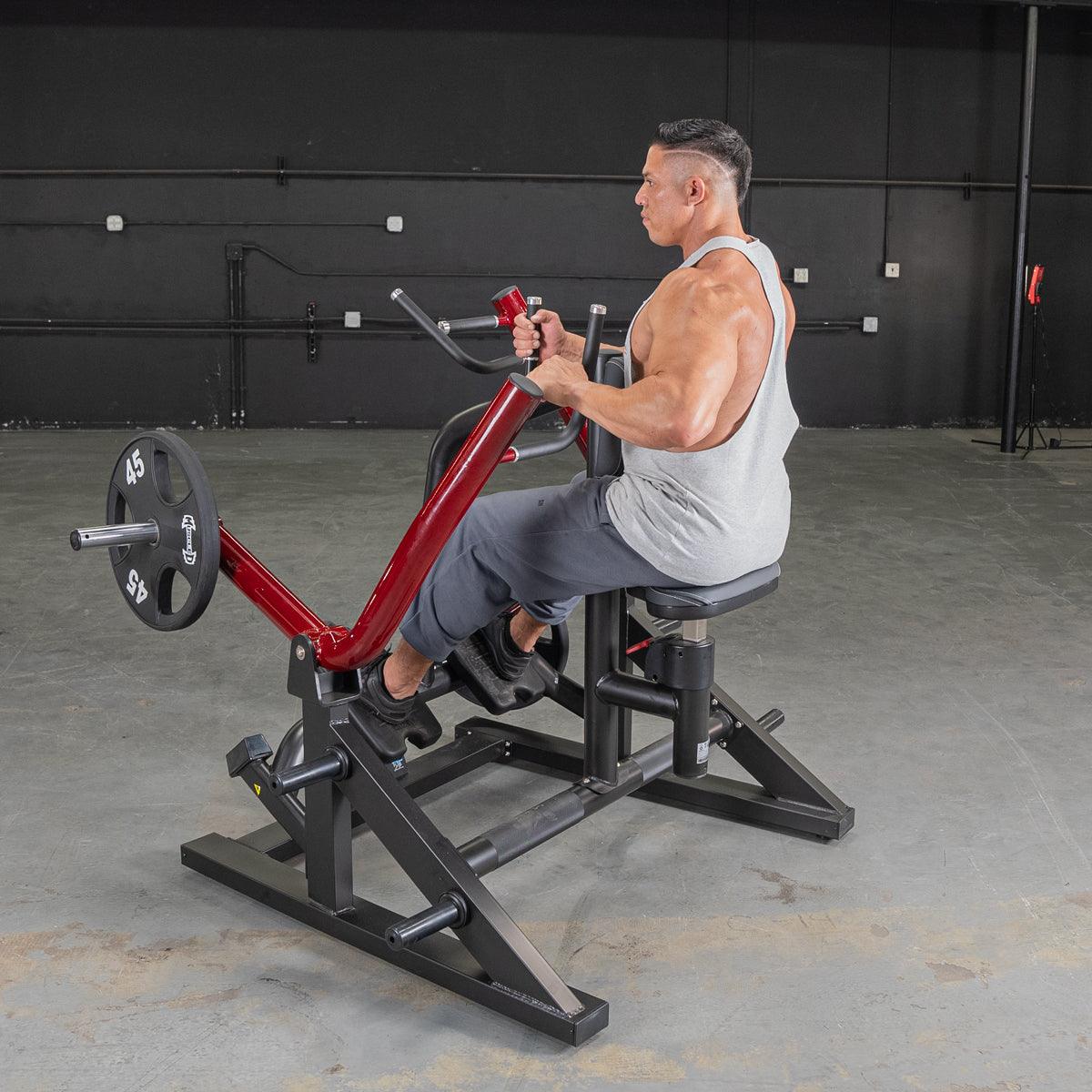 Man in a tank top using a red and black seated row machine with a 45lb weight plate.