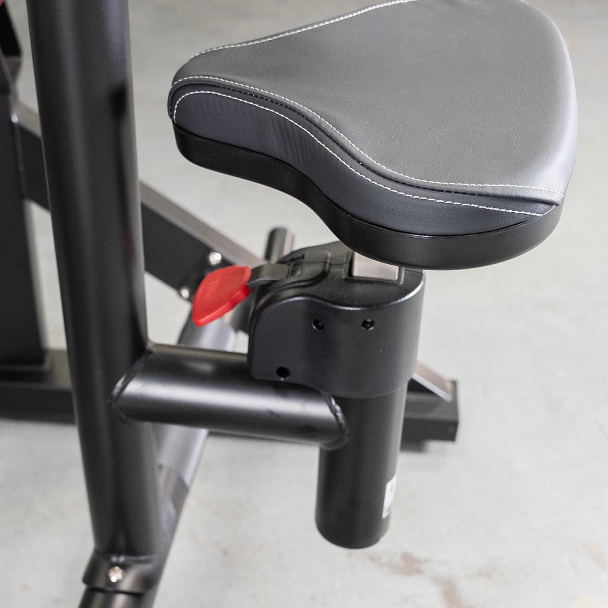 Close-up of the black padded seat with white stitching and red adjustment lever on the seated row machine.