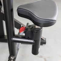 Thumbnail for Close-up of the black padded seat with white stitching and red adjustment lever on the seated row machine.