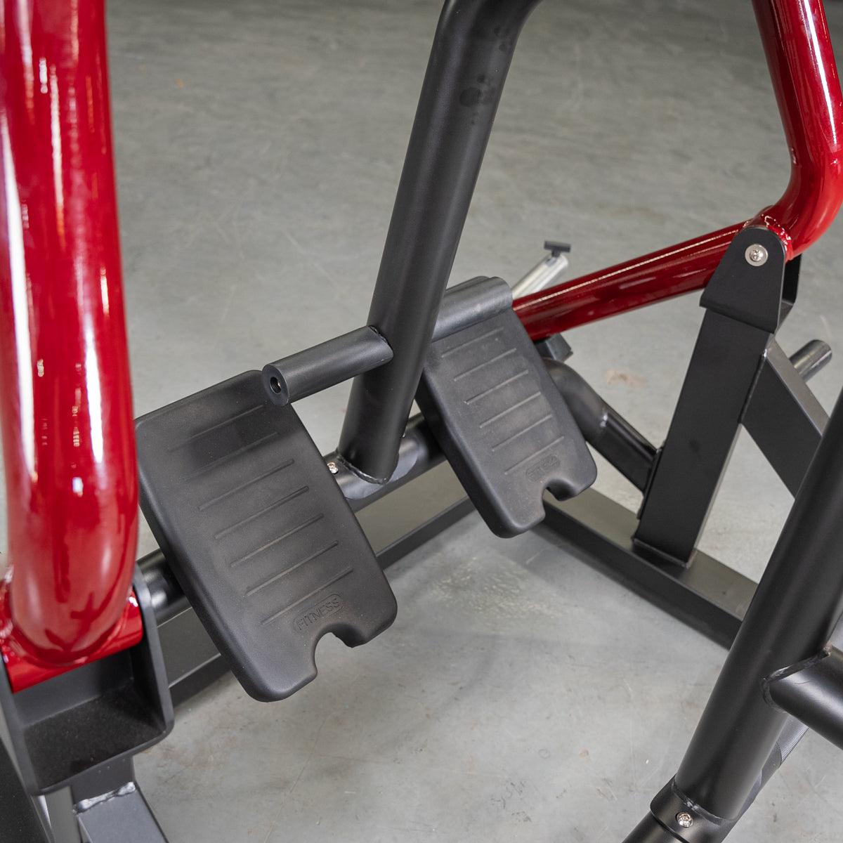 Close-up of the black footplates and red frame of a seated row fitness machine.
