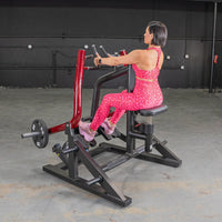 Thumbnail for Woman in pink leopard print using a red and black seated row machine with a 25lb weight plate.