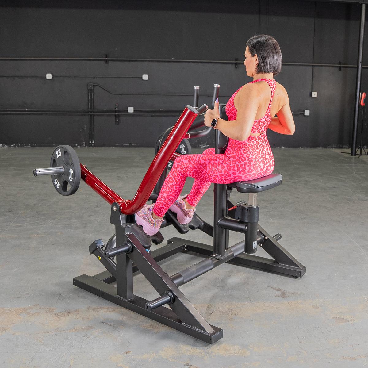 Woman in pink leopard print workout gear using a red and black seated row machine.