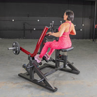 Thumbnail for Woman in pink leopard print using a red and black seated row machine with a 25lb weight plate.