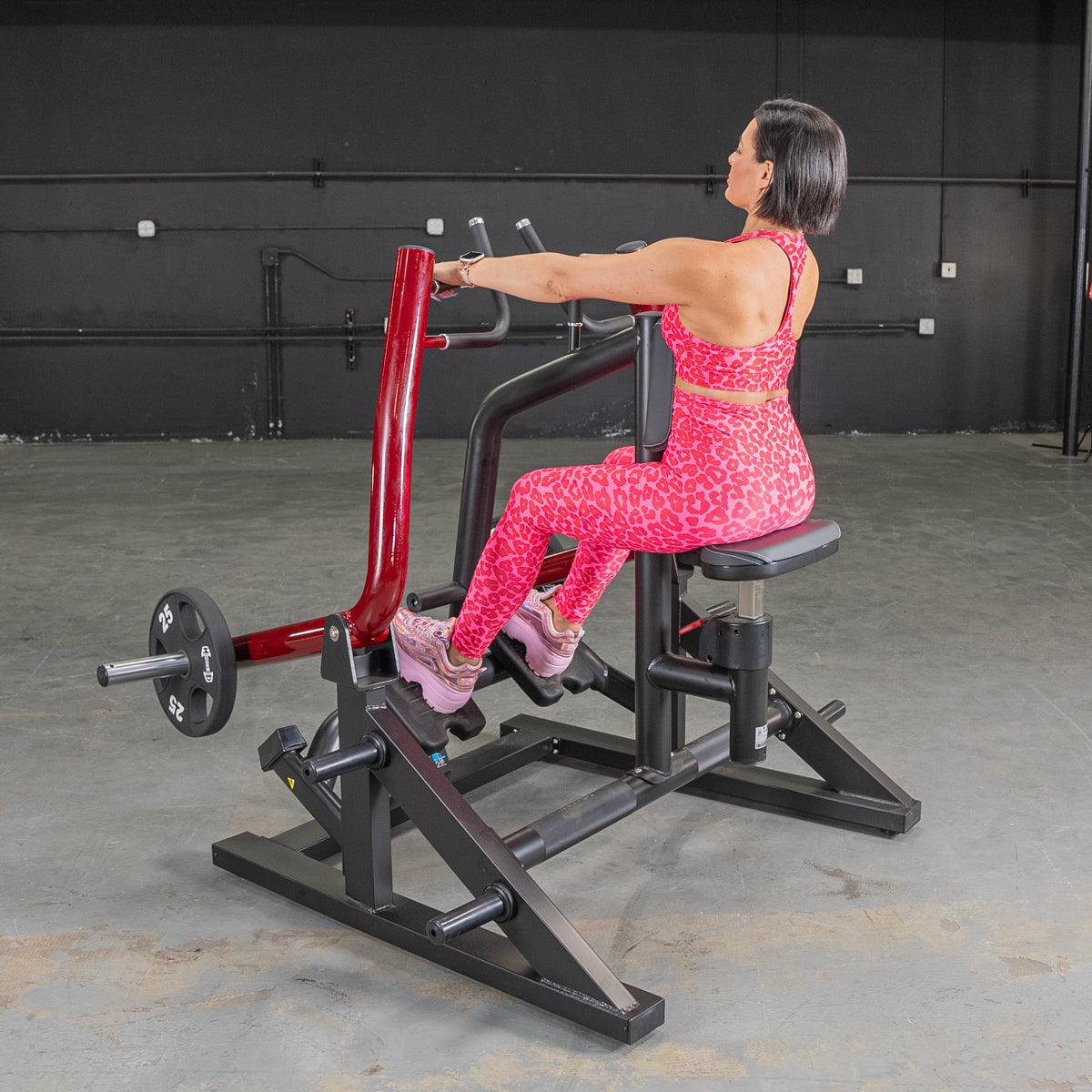 Woman in pink leopard print workout gear using a black and red seated row machine with weights.