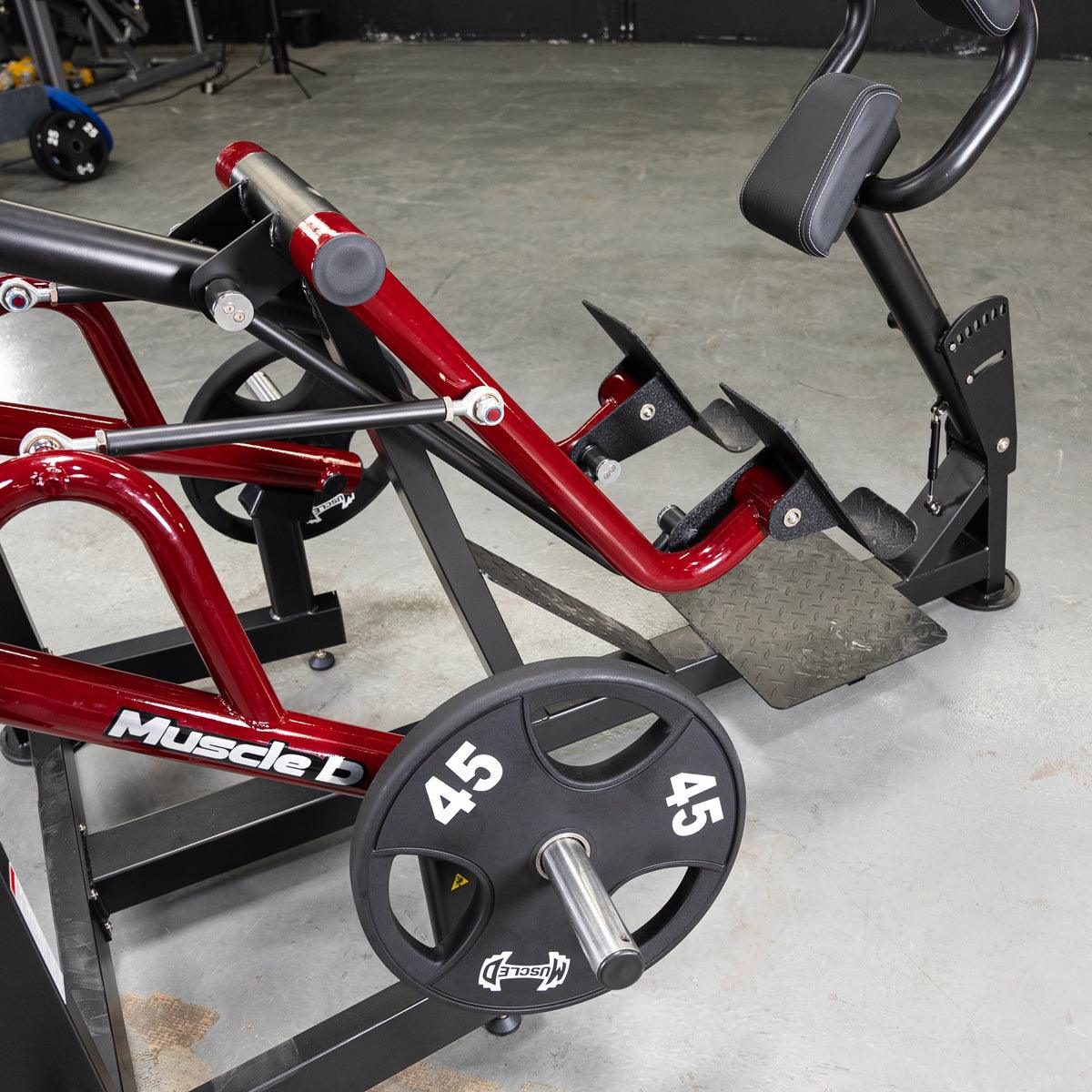 Red and black iso-lateral sprint trainer with 45lb weight plates on a concrete floor.