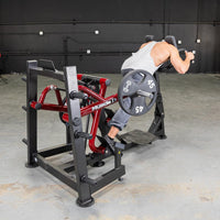 Thumbnail for Man using a red and black iso lateral sprint trainer with a 45lb weight plate in a gym.