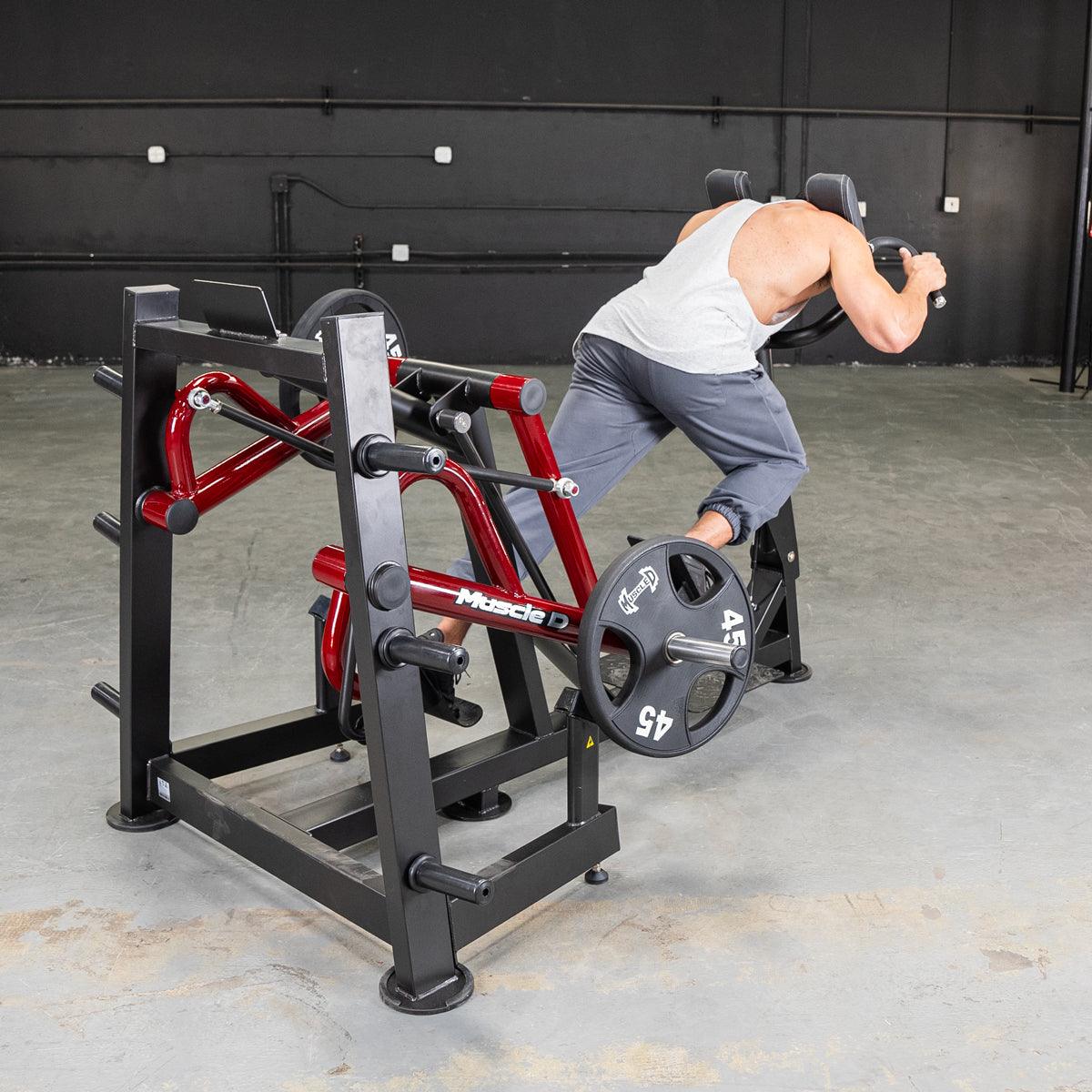 Man using a red and black iso lateral sprint trainer with weight plates in a gym.
