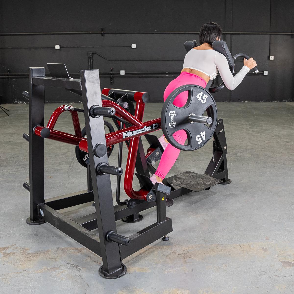 Woman in pink leggings using a red and black iso lateral sprint trainer with a 45lb weight plate.