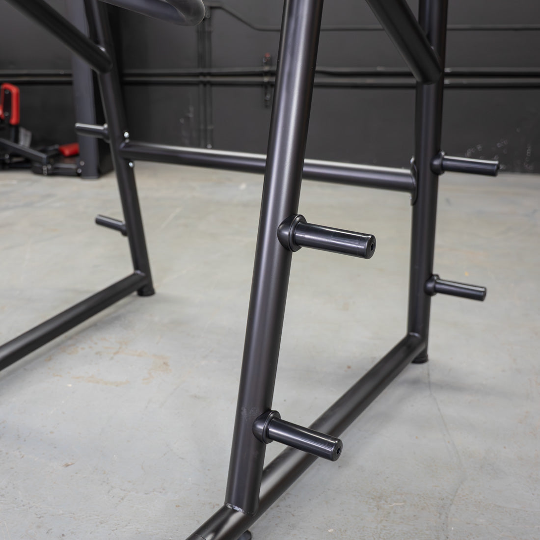 Close-up of black metal frame with several horizontal pegs for weight plates.