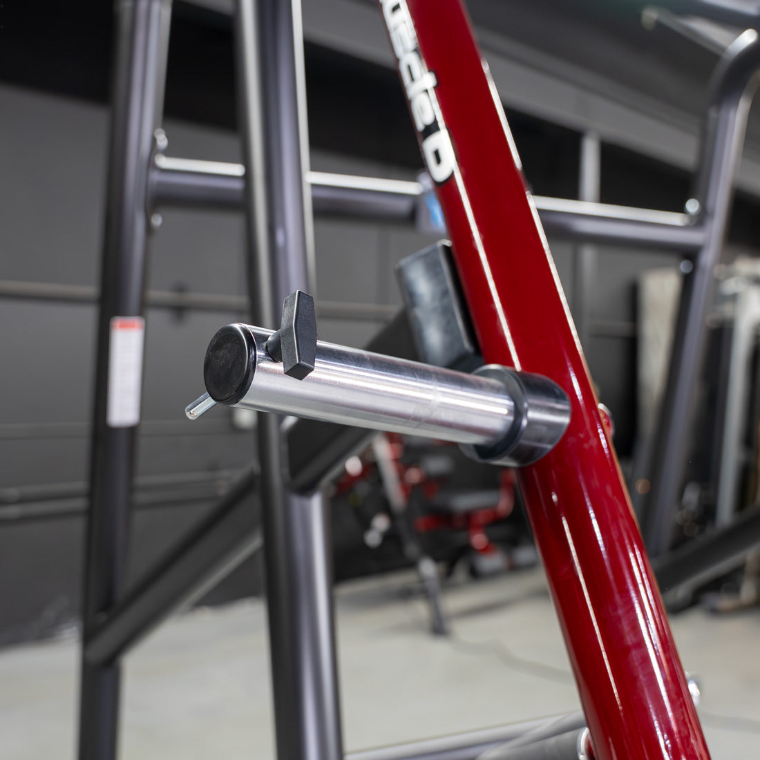 Close-up of a silver weight pin with a black handle inserted into a red and black fitness machine.