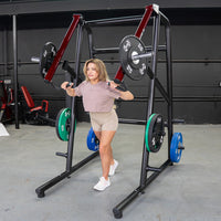 Thumbnail for Woman using a black and red jammer strength trainer with weight plates in a gym.